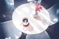 A white cup of black coffee on white table with bunch of red flower decoration in shade and shadow of sun beam Royalty Free Stock Photo