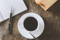 White cup of black coffee with white notebook and pen on wooden table Royalty Free Stock Photo