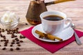 White cup of black hot coffee on saucer, served with coffee beans, white sugar cubes in a bowl, tea spoon, anise and cinnamon stic Royalty Free Stock Photo