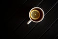 A white cup with black tea and a slice of lemon stands on a dark wooden table. View from above. Minimalism Royalty Free Stock Photo