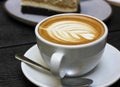 White cup of caffe latte with rosetta latte art, teaspoon and saucer Royalty Free Stock Photo