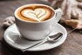 Cup of cappuccino coffee with a heart pattern in a white cup on a saucer with a spoon on a wooden background Royalty Free Stock Photo