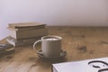 White cup with cappuccino coffee and a  tower of books on a rustic wooden table Royalty Free Stock Photo