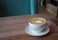 White cup of cappuccino on light wooden table