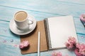 White cup cappuccino with sakura flowers, notebook on a blue wooden table Royalty Free Stock Photo