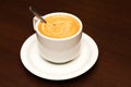 White cup with cappuccino with a spoon on a saucer Royalty Free Stock Photo