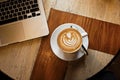 White cup of cappuccino on a wooden table