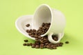 White cup with coffee beans falling on a green background Royalty Free Stock Photo