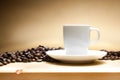 White cup with coffee beans over wood table Royalty Free Stock Photo