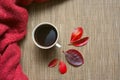 White cup of coffee on a beige background with red autumn leaves.