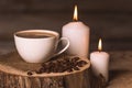 White cup of coffee, candles, and coffee beans