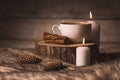 White cup with coffee, candles, cinnamon, fur and cones