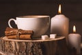 White cup with coffee, candles, cinnamon and sugar