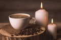 White cup of coffee, candles, and coffee beans