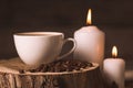 White cup of coffee, candles, and coffee beans