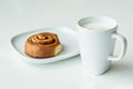 White cup of coffee with freshly baked cinnamon bun roll on a wihte plate Royalty Free Stock Photo