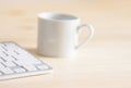 White cup of coffee computer keyboard on wood tabletop. Blurred abstract background for business studying freelance