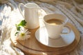 White cup of coffee with cozy knitted plaid on a wooden desk and with white flower Royalty Free Stock Photo