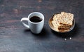 White cup with coffee and crunchy crispbread in a metal bowl on a wooden background, closeup Royalty Free Stock Photo