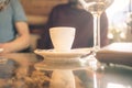 White cup of coffee on a glass table with glasses of wine Royalty Free Stock Photo