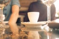 White cup of coffee on a glass table with glasses of wine Royalty Free Stock Photo