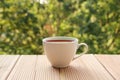 White cup with coffee on a light wooden table against a green summer garden, close-up, copy space Royalty Free Stock Photo