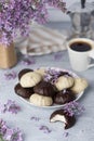 Cup of coffee, lilac, marshmallow in dark and white chocolate glaze on plate, coffee maker