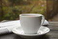 White cup with coffee and newspaper on wooden table, closeup. Morning ritual Royalty Free Stock Photo