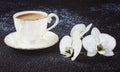 White cup of coffee and white orchid flowers. Composition on a black background Royalty Free Stock Photo