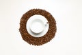 White cup with coffee and plate in the pile of coffee beans on the white wooden background. Royalty Free Stock Photo