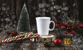 A white cup of coffee and red and green Christmas lollipops in the shape of a heart on a table on a dark background