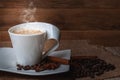 White cup with coffee on a saucer.On the saucer and on the table are coffee beans, anise star and cinnamon stick. Royalty Free Stock Photo