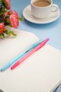 White cup of coffee silver notepad, pink flower on a blue background. Flat lay. copy space Royalty Free Stock Photo