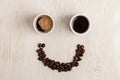 White cup of coffee and smile made of roasted coffee beans on light coloured wooden table Royalty Free Stock Photo