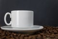 White cup with coffee on sprinkled roasted beans. Black background. Space for text Royalty Free Stock Photo