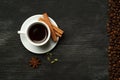 White cup with coffee sticks of cinnamon green cardamom and anise on a black background with coffee beans and place for text top Royalty Free Stock Photo