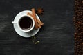 White cup with coffee sticks of cinnamon green cardamom and anise on a black background with coffee beans and place for text top Royalty Free Stock Photo