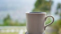 A white cup of coffee or tea object on the table with blur green garden outdoor background. Empty cup for inspirational concept Royalty Free Stock Photo