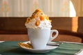 White cup of coffee with whipped cream and dried fruit