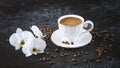 White cup of coffee, white orchid flowers, coffee beans and white candles. Romantic composition on a black background Royalty Free Stock Photo