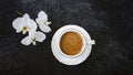 White cup of coffee and white orchid flowers. Romantic composition on a black background Royalty Free Stock Photo