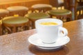 White cup of coffee on a wooden table in a cafe, in the background bar stools. Royalty Free Stock Photo