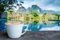 A white cup of coffee on the wooden table by the pool Royalty Free Stock Photo