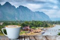 A white cup of coffee on the wooden table with river and mountain background Royalty Free Stock Photo