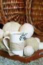 White Cup decorated with twine rope and blue dried flower and white wool threads different sizes balls on wooden tray. cozy warm Royalty Free Stock Photo