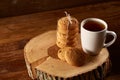 White cup of tea and bunch of cookies on a log over country style wooden background, close-up, selective focus