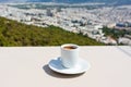 White cup of espresso coffee and view of town of Athens for background