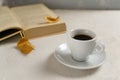 White cup with espresso on a white saucer with a book and autumn leaves on a gray background. Royalty Free Stock Photo