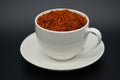 A white cup filled with dried saffron against a dark background Royalty Free Stock Photo