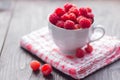 White Cup filled with fresh ripe raspberry on wooden background Royalty Free Stock Photo
